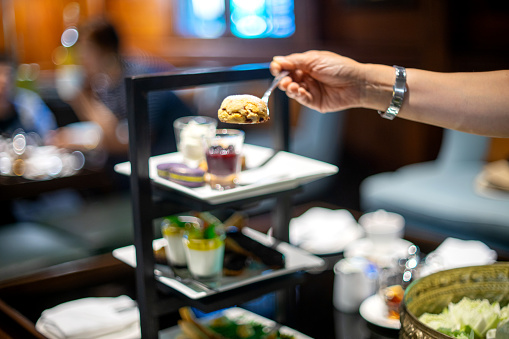 lady hand get food from high tea set on the table in restaurant