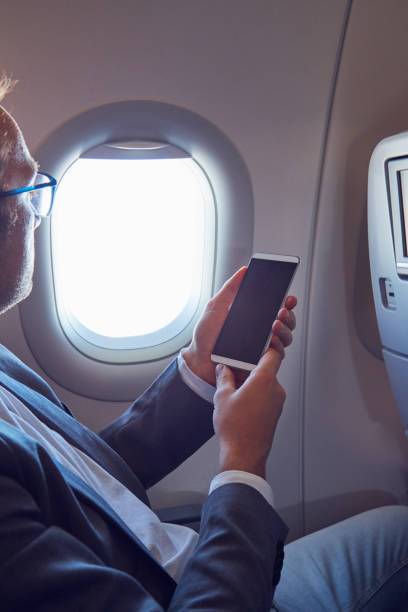 istock Man using cellphone to take photos through the airplane window. 1174565307