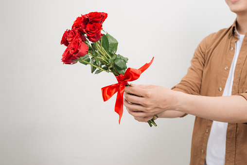 Smiling Asian man holding bunch of roses.