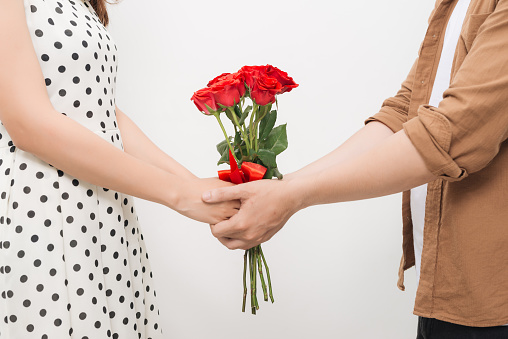 Beautiful young woman hugging her boyfriend and holding nice bouquet of red roses