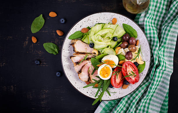 istock Ketogenic diet. Keto brunch. Boiled egg, pork steak and olives, cucumber, spinach, brie cheese, nuts and tomato. Top view 1174567761