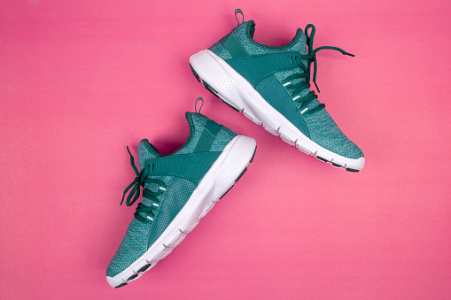 Green sneakers or sport running shoe isolated on a pink background