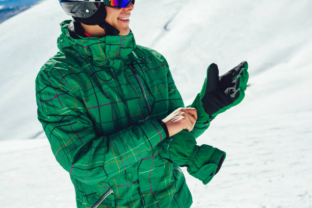 esquiador profesional en un casco con un pasamontañas de pie en un glaciar se está preparando para saltar usando guantes de membrana. - ski insurance fotografías e imágenes de stock