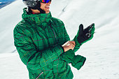 Professional skier in a helmet with a ski mask standing on a glacier is preparing to jump wearing membrane gloves.