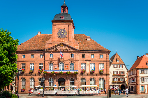 Wissenbourg, France - August 23, 2019: Town hall of Wissembourg in Alsace, France. In front is a small train used by tourists for sightseeing in the village.