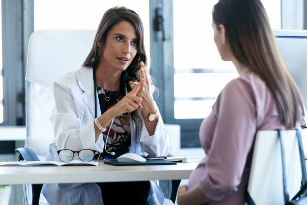 serious young gynecologist giving guidelines to his pregnant patient in the clinic. - prenatal care imagens e fotografias de stock