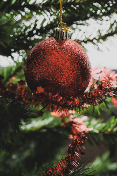 istock Red holiday bauble hanging on decorated tree 1174590519