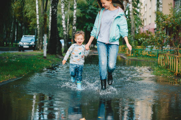 비가 내린 후 웅덩이를 걷고 있는 어머니와 함께 있는 아이. - puddle rain child splashing 뉴스 사진 이미지