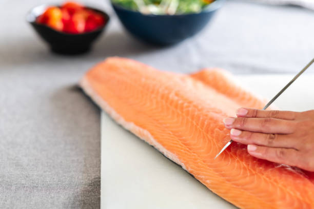 istock Woman chef about to cut raw salmon. 1174590936