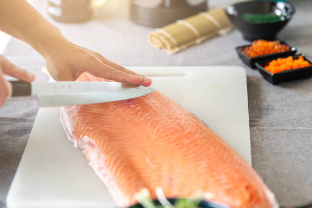 istock Woman chef about to cut raw salmon. 1174590949