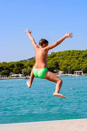Child boy jumping into the sea.