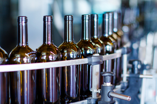 Glass bottles in bottling machine at modern winery
