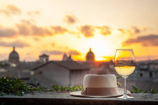 chapéu, vidro e frasco do vinho branco na frente da vista panorâmico da arquitectura da cidade de roma do terraço do campidoglio no por do sol. marcos, abóbadas de roma, italy. - rome vatican italy city - fotografias e filmes do acervo