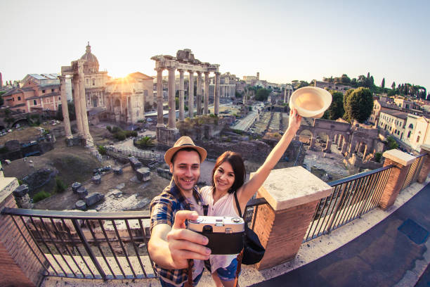 turista novo dos pares que olha o fórum romano no nascer do sol e o beijo que toma o selfie. foro imperial histórico romano em roma, italy do ponto de vista panorâmico. - travel tourist roman forum rome - fotografias e filmes do acervo