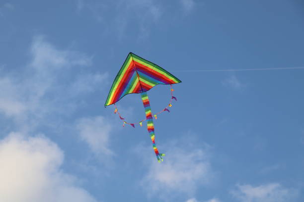 istock Bright rainbow kite flying in blue sky with clouds 1174603064