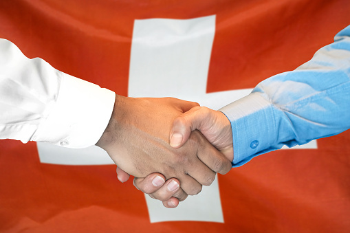 Business handshake on Switzerland flag background. Men shaking hands and Switzerland flag on background. Support concept