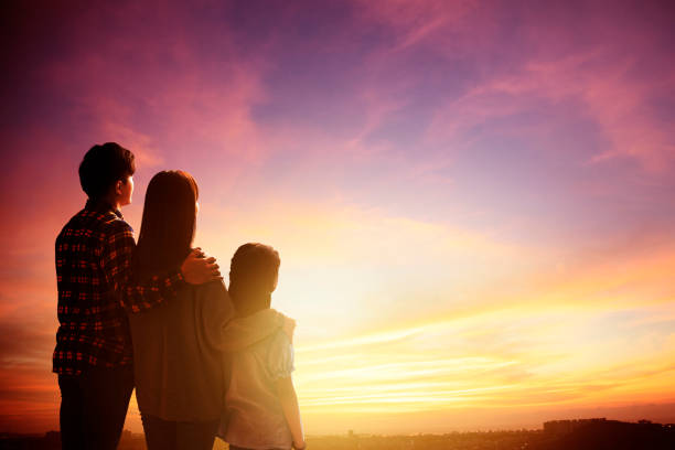istock rear view family standing and watching the sunset 1174606698