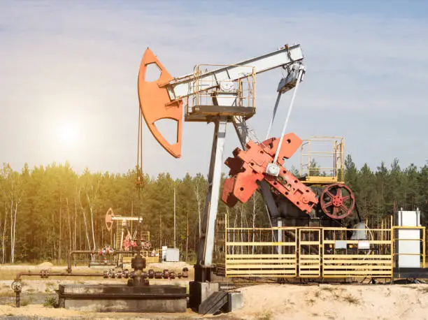 Oil well for the production of oil and gasoline and gas on the background of the forest, the production of gasoline, pumpjack, extraction of petroleum