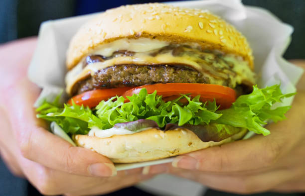 istock Fast food. Woman holding freshly cooked burger. 1174613332
