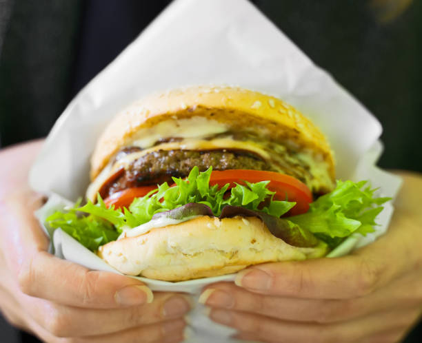 istock Fast food. Woman holding freshly cooked burger. 1174613346