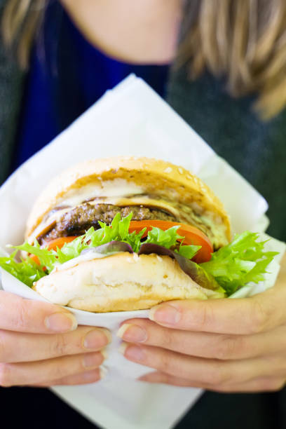 istock Fast food. Woman holding freshly cooked burger. 1174613353