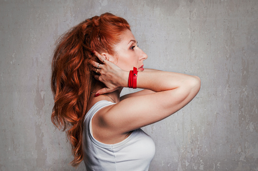 Beautiful young red-haired woman in a white T-shirt in profile, studio portrait