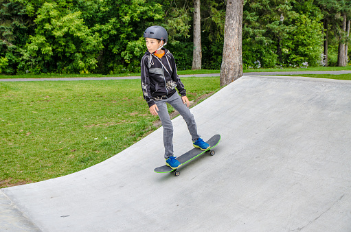 Boy at skatepark going up ramp during summer day