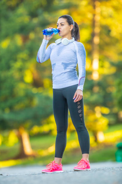 istock Young female athlete drinks water after training. 1174614700