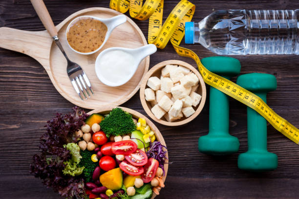 insalata di verdure fresche e cibo sano per attrezzature sportive per le donne dieta dimagrante con rubinetto di misura per la perdita di peso su sfondo legno. concetto di sport sano - food and drink foto e immagini stock