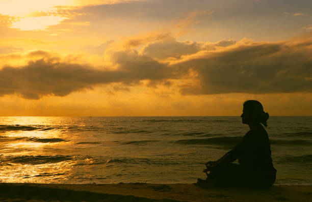 istock Indian woman meditating on morning sunrise beach 1174620130