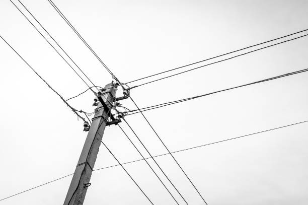 istock Low Angle Black and White Image of a Concrete Utility Power, Electricity Pole with Insulators and Cables. 1174620390