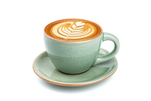 Side view of hot latte coffee with latte art in a ceramic green cup and saucer isolated on white background with clipping path inside.