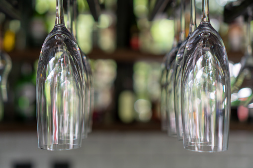 A lot of champagne glass hanging on a rack with blurred background