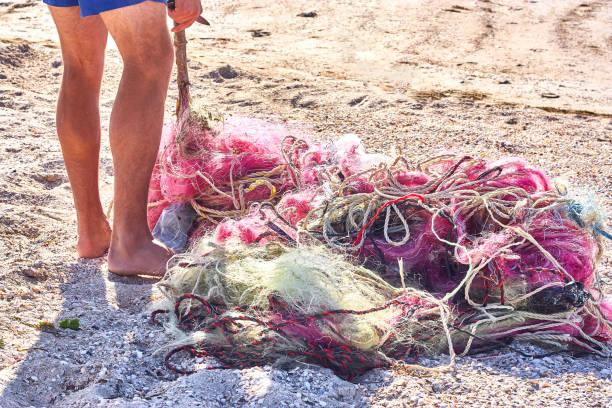 un enredado lío de redes de pesca cuerda de plástico y otros escombros lavados en una playa costera. - commercial fishing net netting fishing striped fotografías e imágenes de stock