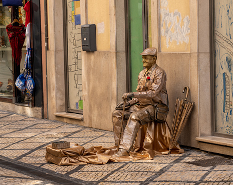 Coimbra, Portugal - 11 August 2019: Living statue actor dressed in gold and playing part of an old tourist