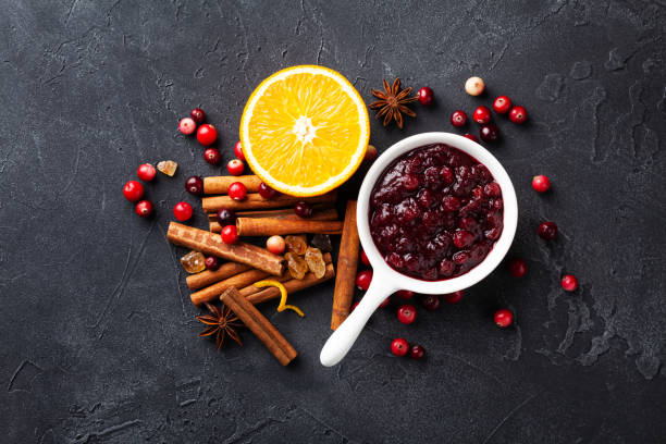 istock Cranberry sauce in ceramic saucepan with ingredients for cooking on stone table top view. 1174640337