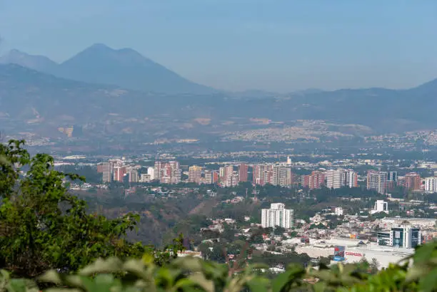 Photo of Panoramic view of Guatemala City at sunrise, Latin American city surrounded by volcanoes and green areas.