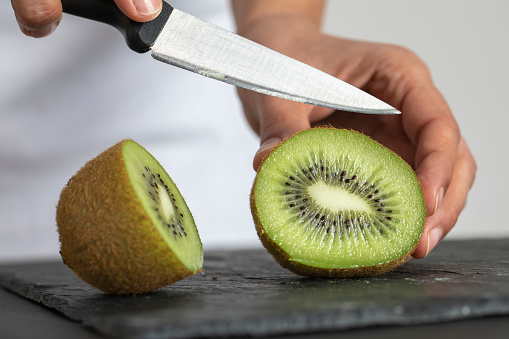 Golden kiwi fruit close-up on cutting board. Slices of sweet ripe organic golden kiwi close up on light grey background