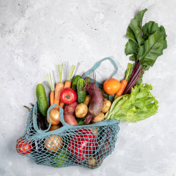 istock Top view of string bag with fresh farm vegetables on grey concrete background. 1174643515