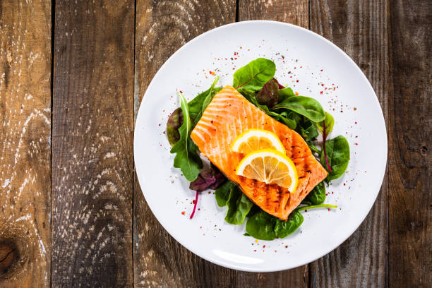 Grilled salmon on fresh vegetables on wooden table