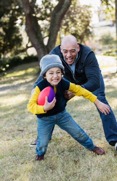 istock Hispanic boy and father playing with football 1174651092