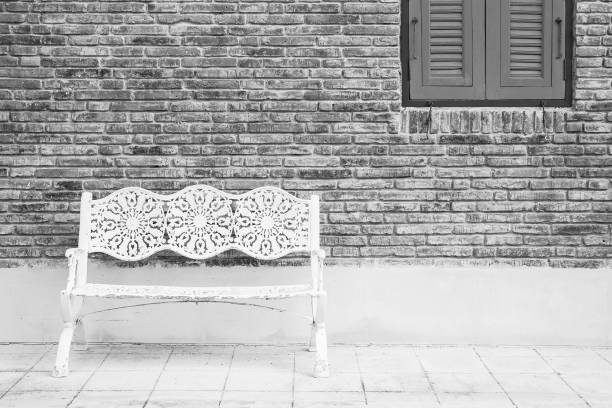 White metal long chairs, the background is brown brick blocks To the right is a vintage style blue pane.