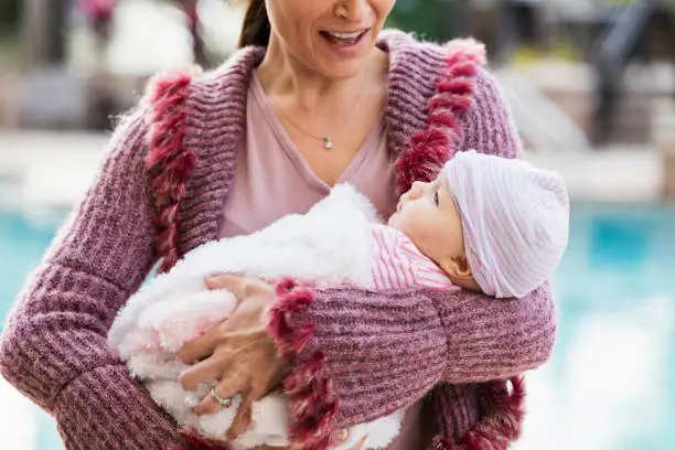 Photo of Mother holding baby girl bundled in blanket