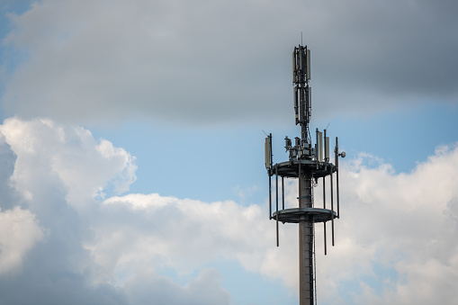 A radio mast for  signals from cell phones and other devices with blue sky and clouds