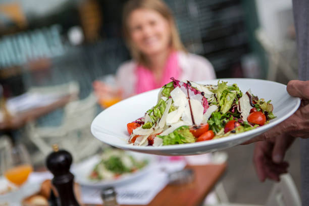 Close up photo of waiter serving salad for woman, selective focus