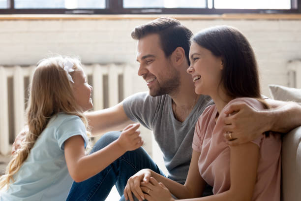 istock Side view happy couple sitting on floor, talking with daughter. 1174655333