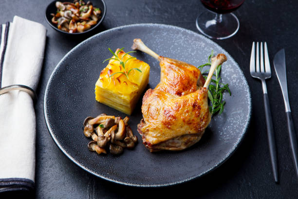 istock Duck legs confit with potato gratin and mushroom on a plate. Slate background. 1174656423
