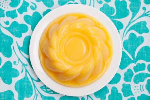 Mango pudding, jelly on white plate Blue textile background. Top view. Copy space
