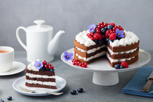 Chocolate cake with whipped cream and fresh berries. Grey stone background