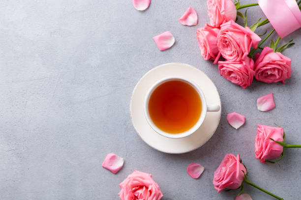 Cup of tea with pink rose. Top view. Copy space. Grey stone background.
